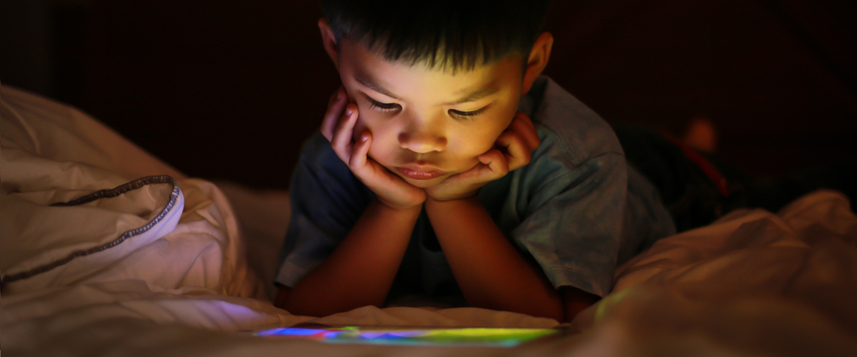 A child watching a screen in the dark.