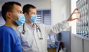 Two surgeons look at MRI scans of the spine