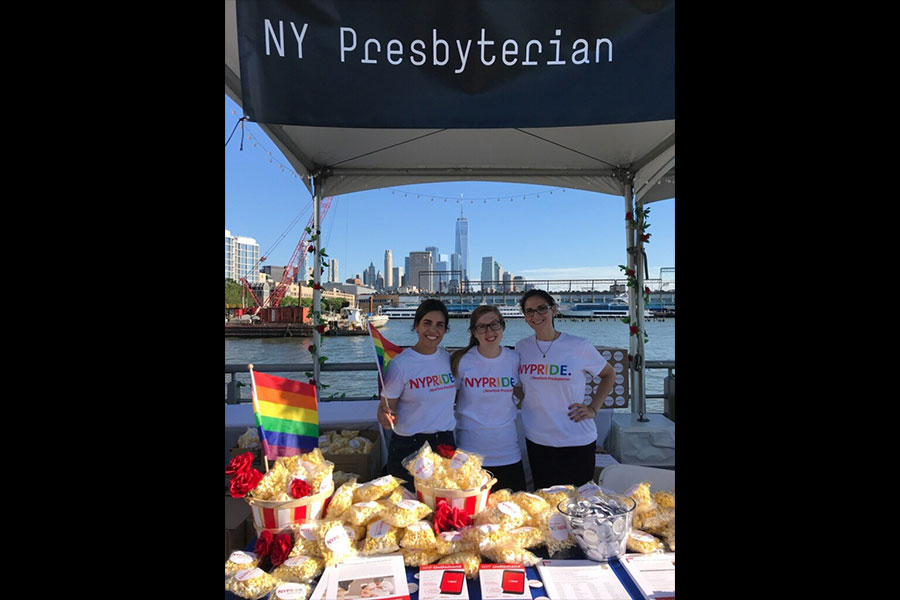 Three women posing for a photo under the NewYork-Presbyterian booth.