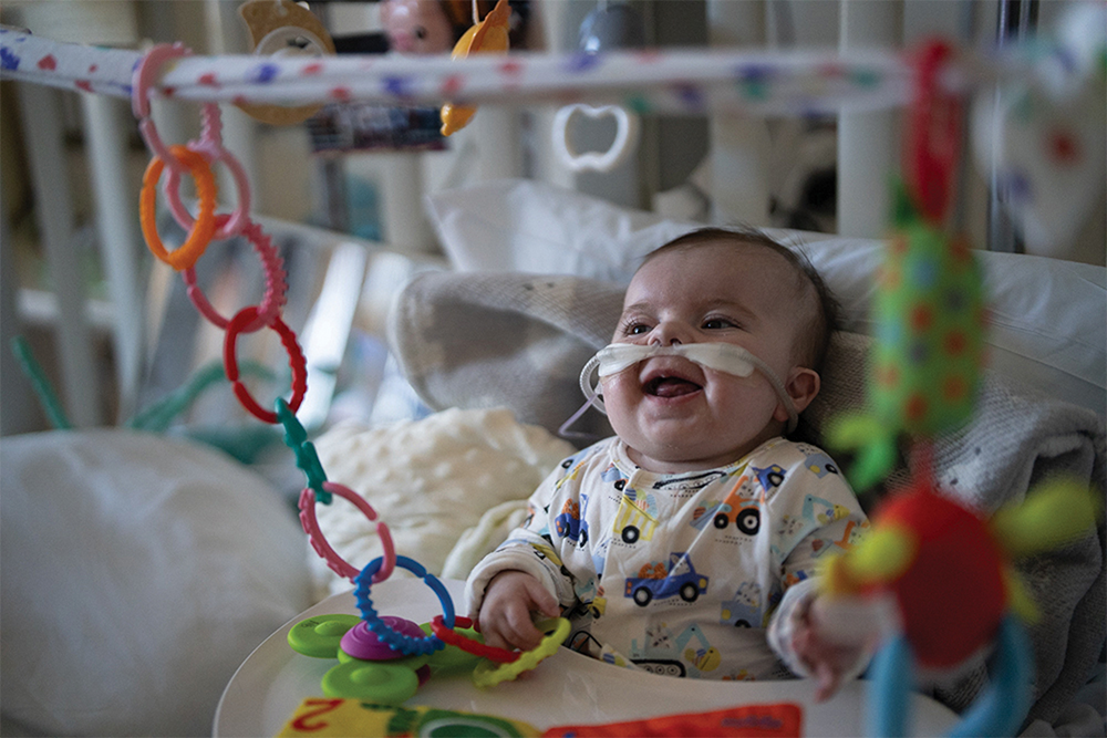 Smiling baby in a bed surrounded by toys.