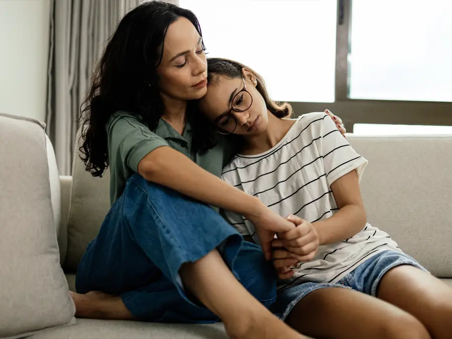 girl leaning on adult woman on couch