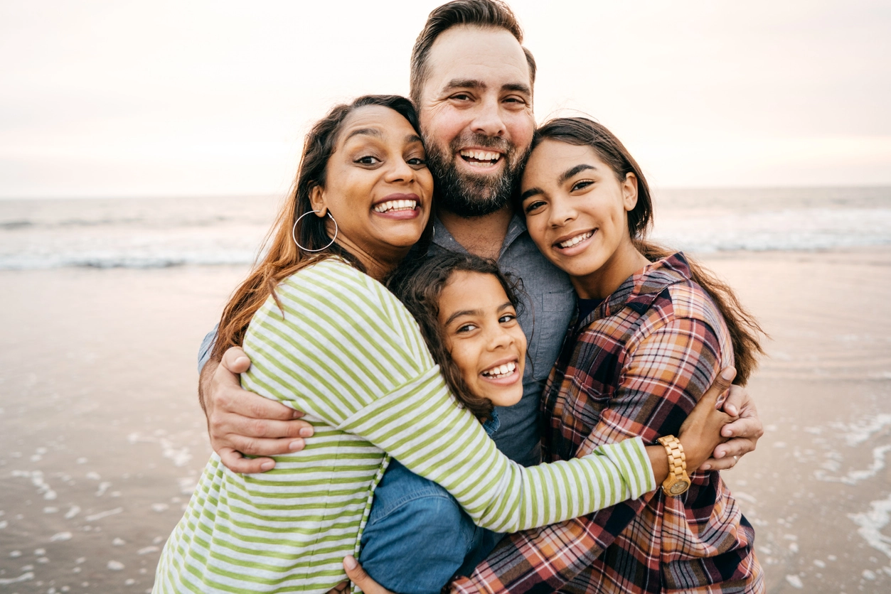 family of four embacing eachother on the beach